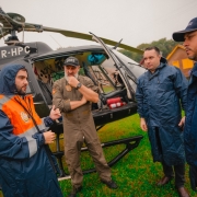 Primeiro dia do Gabinete de Crise em Santa Cruz do Sul. Gabriel conversa com outros três homens diante de um helicóptero.