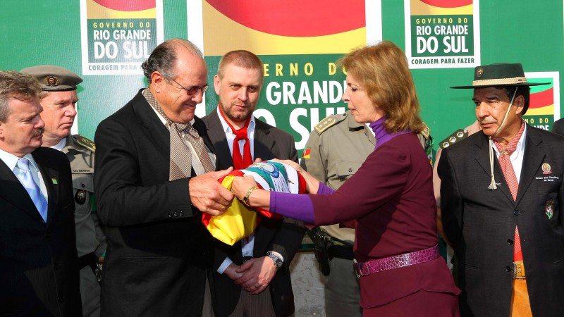 A governadora Yeda Crusius, entrega a bandeira do Estado ao presidente da Confederação Brasileira da Tradição Gaúcha (CBTG), Décio Albino de Oliveira.