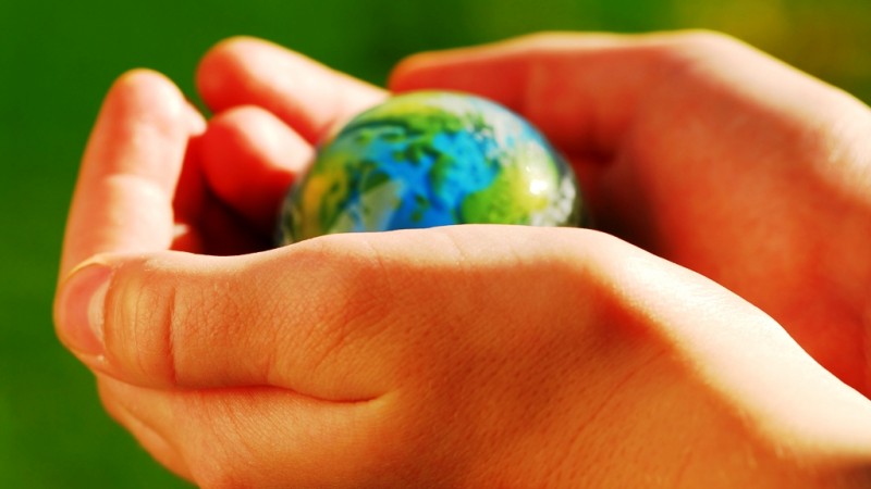 Child's hands holding a globe on green background