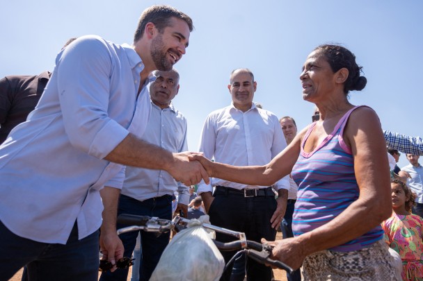 Governador Eduardo Leite aperta a mão de uma senhora que segura uma bicicleta durante visita às obras de ampliação da avenida Caverá, em Alegrete