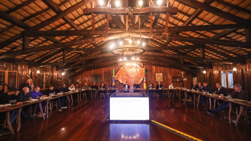 Governador Leite ao centro, rodeado por integrantes da bancada gaúcha, todos sentados à mesa no Galpão Crioulo