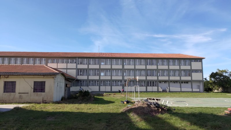 &Agrave; frente, na esquerda, est&aacute; o pr&eacute;dio antigo; ao fundo, o novo, mais alto. H&aacute; tamb&eacute;m um gramado e uma quadra poliesportiva &agrave; direita