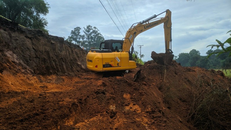 Escavadeira de cor amarela trabalha em meio &agrave; terra