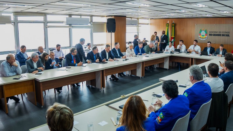 Em uma mesa em forma de U estão diversos representantes de entidades da sociedade civil em reunião com o governador Eduardo Leite por causa das chuvas de setembro. A foto foi tirada na diagonal da direita para esquerda. 