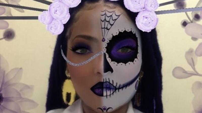 Imagem em close do rosto de uma mulher com o rosto todo maquiado a partir de uma est&eacute;tica de caveira e de festa de Halloween.