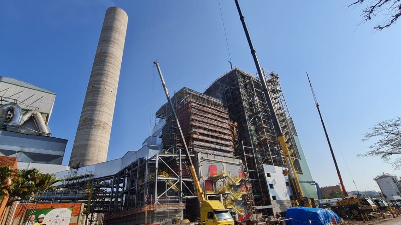 Imagem externa. Ao centro, estão as fachadas em obras de dois edifícios da planta industrial CMPC Celulose Riograndense. Ao lado esquerdo da imagem, há uma torre circular.