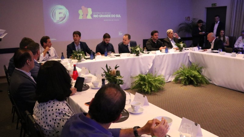 Foto em ambiente fechado. Em uma mesa retangular, estão diversas autoridades. Ao centro da mesa, está o vice-governador.