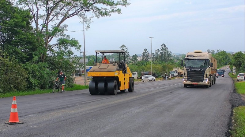 Foto de uma rodovia em obras, com máquinas e um caminhão na pista.