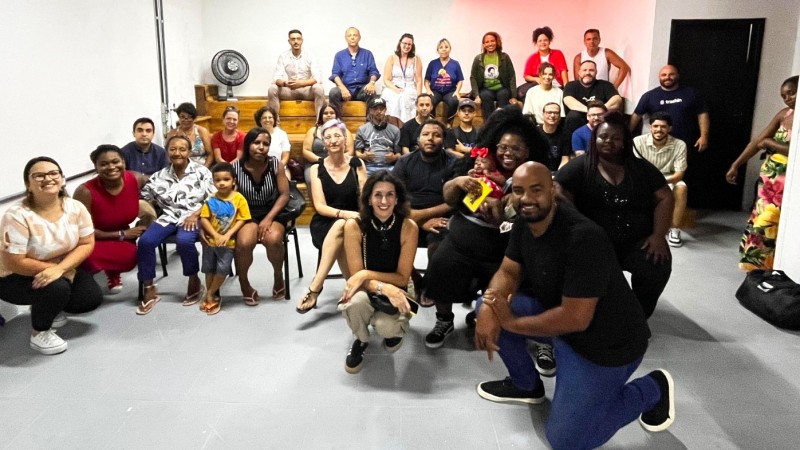 Diversas pessoas que participaram do encontro em foto posada. Todos estão reunidos, alguns estão agachados, outros estão sentados e outros estão em pé.