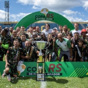 Foto possa de vários jogadores reunidos após receberem o troféu da primeira Copa RS de Futebol Amador.