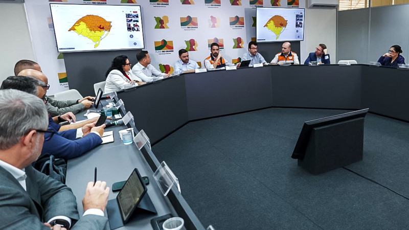 Foto aberta de várias pessoas sentadas em U À mesa durante a reunião.