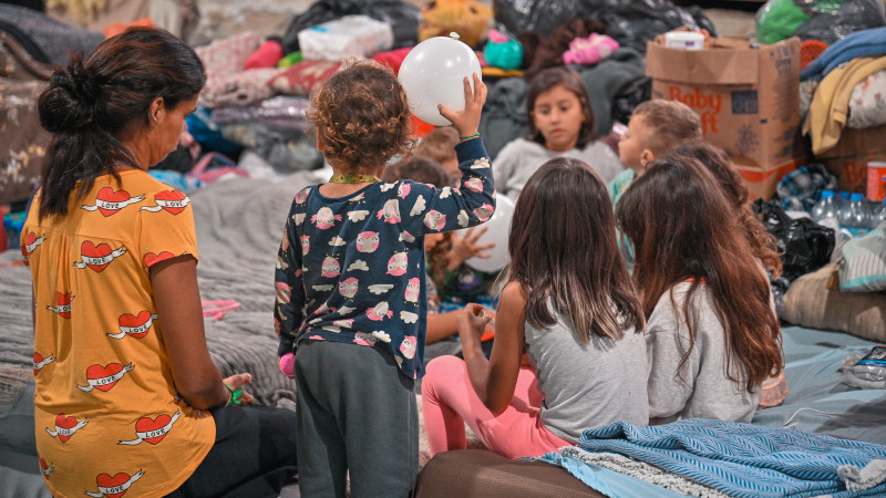 Crianças brincando com um balão em um abrigo.