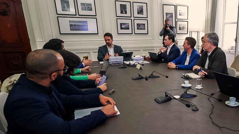 Reunião para anúncio de projeto de adoção de animais resgatados nas enchentes. Leite, Gabriel e secretários reunidos em torno de uma mesa. Leite está falando e gesticulando.