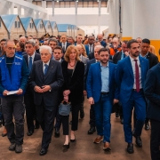 Leite, Gabriel e o presidente da Itália com muitas pessoas atrás deles enquanto percorriam o espaço do Centro Recomeço.