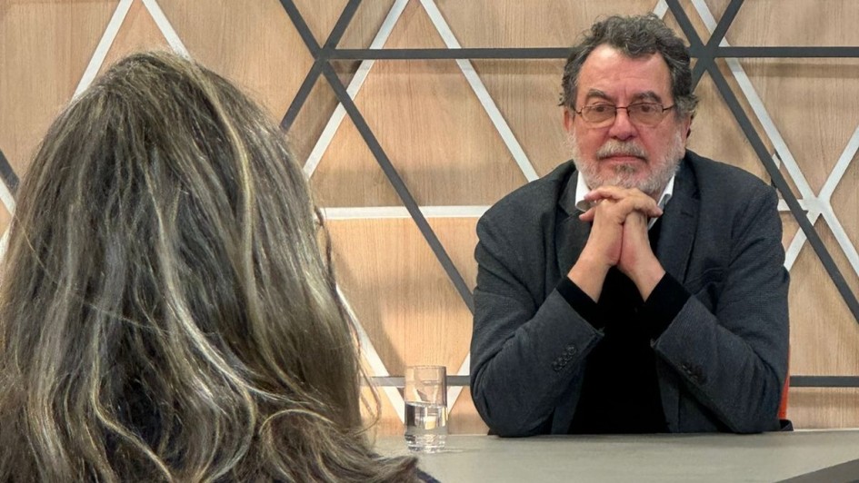 Imagem de Jorge Furtado de frente à direita da imagem sendo entrevistado. A entrevistadora aparece de costas mais à esquerda da imagem.
