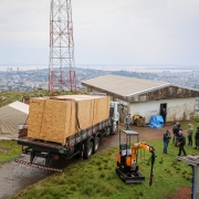 Imagem que mostra a carreta carregando uma enorme caixa onde está o radar chegando ao alto do morro onde o equipamento será instalado.