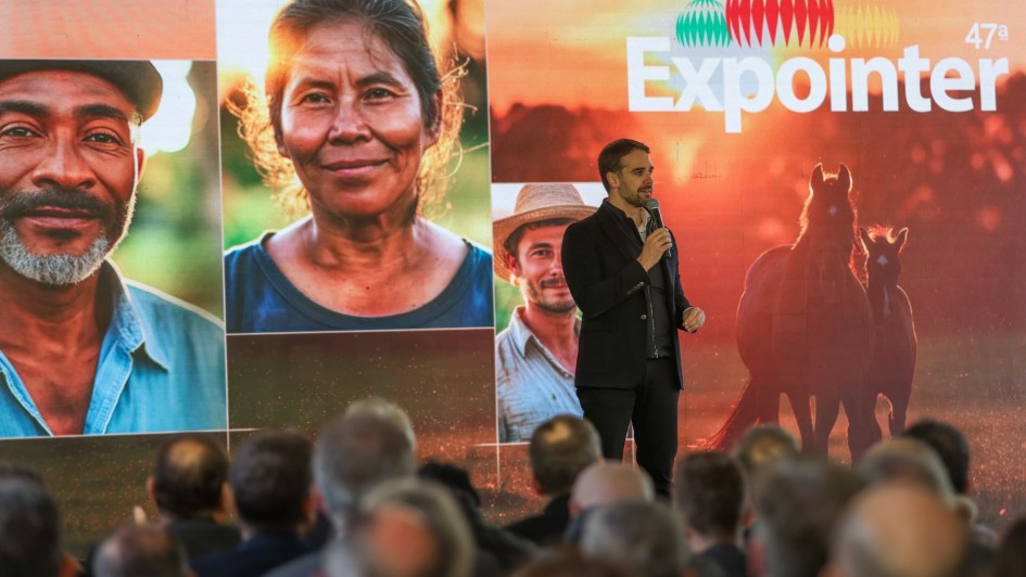 Leite ao microfone e em pé sobre um palco falando Lançamento da Expointer 2024. Parte da platei pode ser vista de costas. Há um grande painel atrás de Leite com imagens de rostos de produtores rurais e onde está escrito 47ª Expointer.