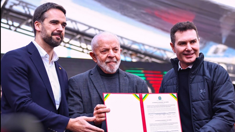 Lula, Leite e outro homem seguram o documento recém assinado em evento de entrega de casas em Porto Alegre.