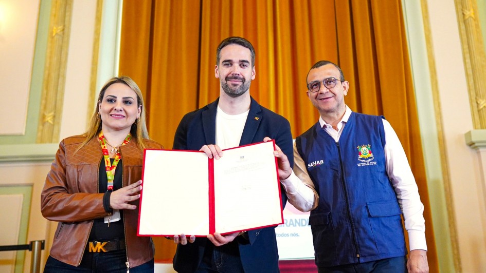 Foto posada. Leite segura o documento recém assinado juntamente com os secretários Danielle Calazans e Carlos Gomes no lançamento da Estratégia Integrada de Habitação.