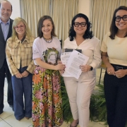 Foto posada com duas pessoas segurando o documento assinado e outras três que participam do ato.