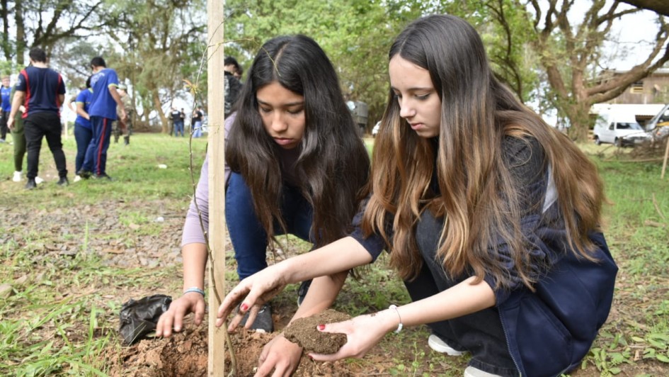 Duas adolescentes plantando uma muda de árvore durante a ação.