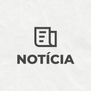 Card com o título "NOTÍCIA" no centro, com um ícone de jornal logo acima da palavra. No canto inferior direito, está o logotipo do governo do Estado do Rio Grande do Sul, que apresenta silhuetas coloridas de três pessoas (em verde, vermelho e amarelo). As cores verde, vermelha e amarela também aparecem no canto superior esquerdo. O fundo da imagem é claro e texturizado.