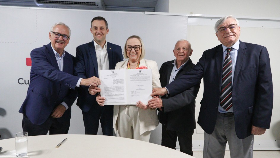 Arita e mais quatro homens segurando o documento recém assinado, em foto posada.