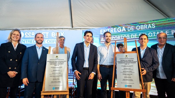 Foto posada de Leite e outras pessoas junto às placas de inauguração dos dois aeroportos.