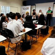 Alunos de costas em uma sala de aula com quatro pessoas falando com eles na parte da frente da sala de aula.