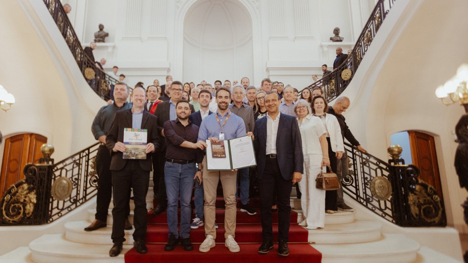 Foto posada na escadaria interna do Palácio Piratini após anúncio de investimento em poços e redes de distribuição de água. Leite e o vice-governador seguram o documento recém-assinado