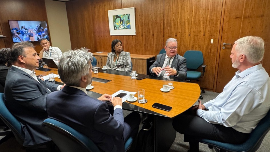 Imagem de pessoas sentadas em torno de uma mesa em reunião.