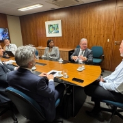 Imagem de pessoas sentadas em torno de uma mesa em reunião.