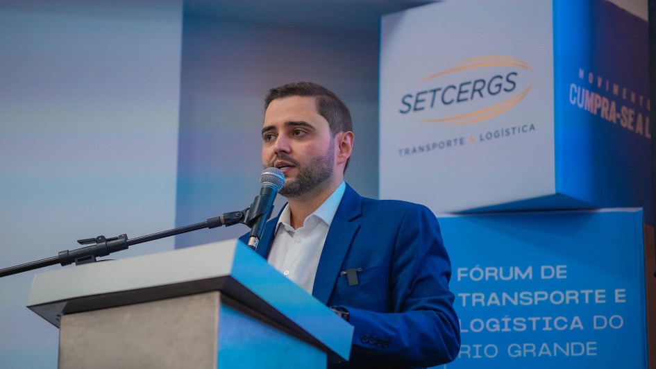 Gabriel falando ao microfone, em close, atrás de um púlpito no Fórum de Transporte e Logística do RS 2025