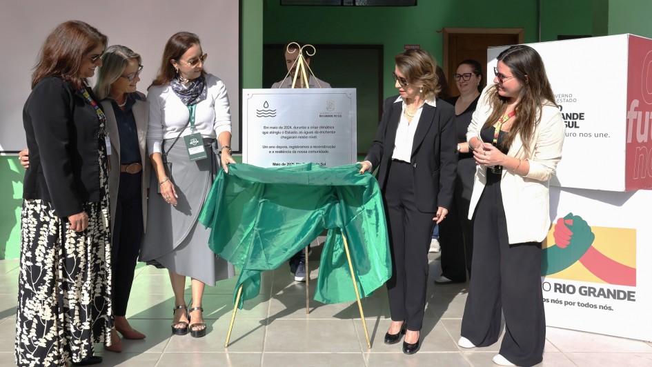 Cinco mulheres fazendo o decerramento de uma placa na Escola Américo Braga de Eldorado do Sul em 2025.