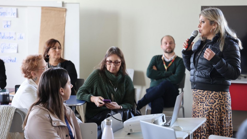 Uma mulher ao microfone em uma sala de aula em meio aos participantes da formação de mediadores educacionais de 2025.