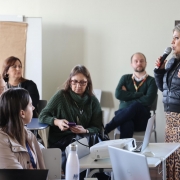 Uma mulher ao microfone em uma sala de aula em meio aos participantes da formação de mediadores educacionais de 2025.