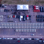 Foto aérea, tirada por drone, que mostra uma grande quantidade de viaturas alinhadas em fileiras simétricas. Há uma concentração de pessoas reunidas em frente a um palco, onde há uma tenda branca. Ao lado do palco, vê-se um helicóptero exposto. Toda a cena acontece em um pátio grande e aberto, cercado por áreas verdes.