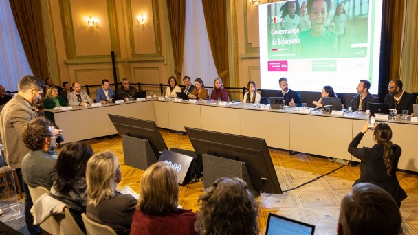 Imagem aberta de diversa pessoas sentadas em U durante a reunião de governança da educação em maio de 2025.