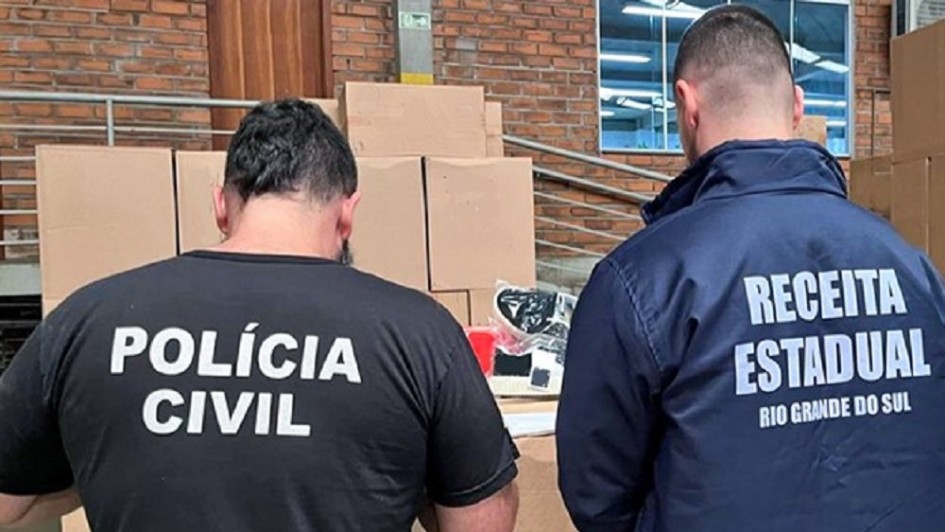 Imagem de dois agentes de costas conferindo mercadorias apreendidas na Operação Fronteira 2025.