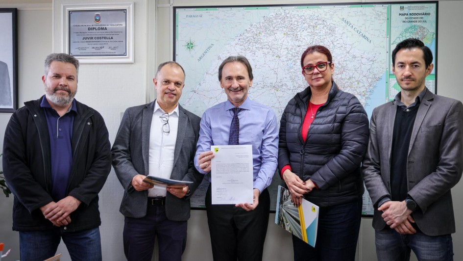 Foto posada com participantes do ato em pé, de frente, exibindo o documento assinado.