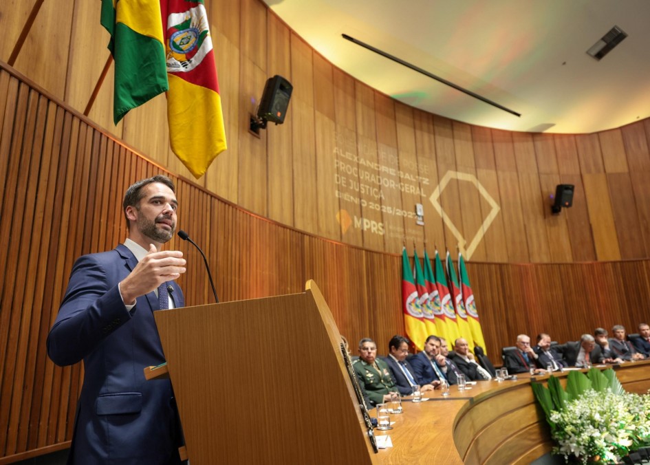 Leite ao microfone atrás de um púlpito falando na recondução de Saltz a procurador-geral de Justiça. Diversas autoridades são vistas sentada na tribuna de honra e atentas à fala do governador.