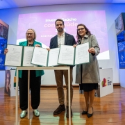 Foto posada em que Leite e outras duas mulheres seguram os documentos recém assinados.