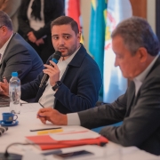 Gabriel  com o microfone falando entre dois homens em reunião sobre política habitacional com o governo federal em 2025.