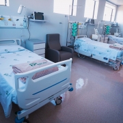 A imagem retrata um quarto de hospital com três leitos de UTI totalmente equipados. Cada cama possui roupa de cama com a marca do SUS e do Governo Federal, e está acompanhada de equipamentos médicos como monitores, bombas de infusão e suportes de soro. O ambiente é limpo, organizado e pronto para atender pacientes em cuidados intensivos.