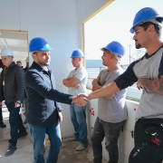 A imagem mostra o vice-governador Gabriel Souza cumprimentando um trabalhador em um canteiro de obras, cercado por outros profissionais com capacetes. O ambiente sugere uma vistoria em andamento, destacando o clima de colaboração e progresso na construção.