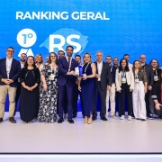A imagem mostra um grupo de cerca de 20 pessoas reunidas, sorrindo e posando para a câmera. Ao centro, está o governador Eduardo Leite e a titular da SPGG, Danielle Calazans, segurando um troféu. No painel ao fundo, pode-se ler "Ranking geral - 1º lugar: RS". 