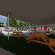 : A foto mostra uma maquete de um pátio de escola com um banco curvo de madeira. A área é pavimentada com peças de concreto em tons de cinza. Ao redor do banco, há vasos de plantas com pequenas árvores. Ao fundo, um prédio moderno com grandes janelas e detalhes em amarelo.
