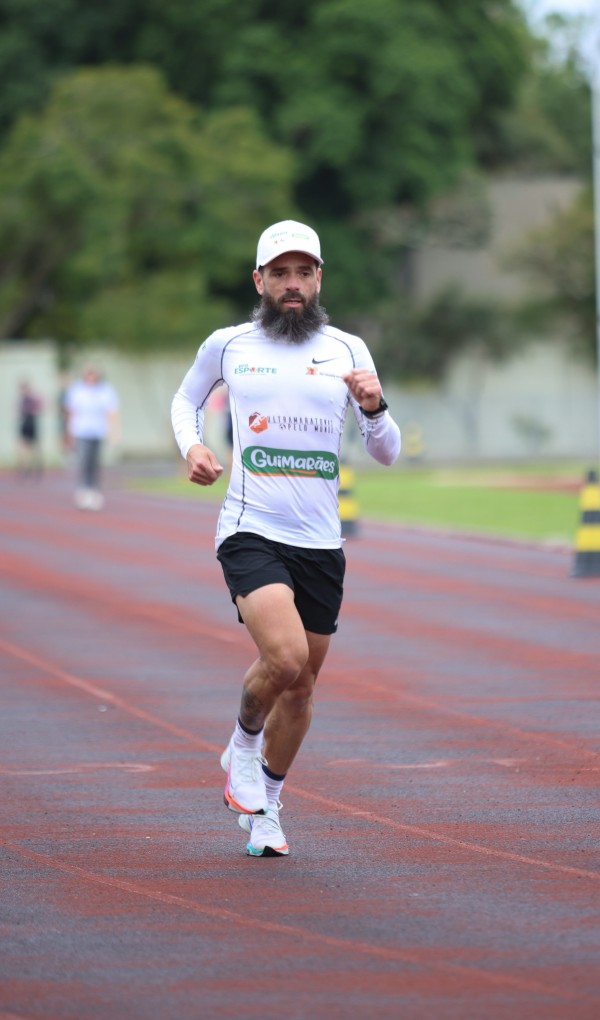 Foto vertical de corpo inteiro de Tiarles correndo na pista ao ar livre.