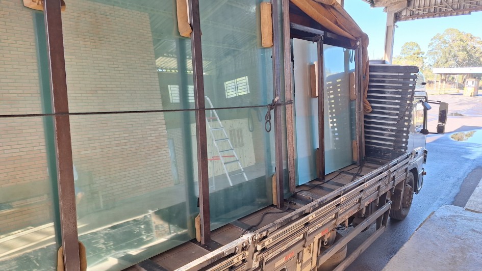 Foto de um caminhão com carga composta de vidros, que aparecem em destaque na imagem.