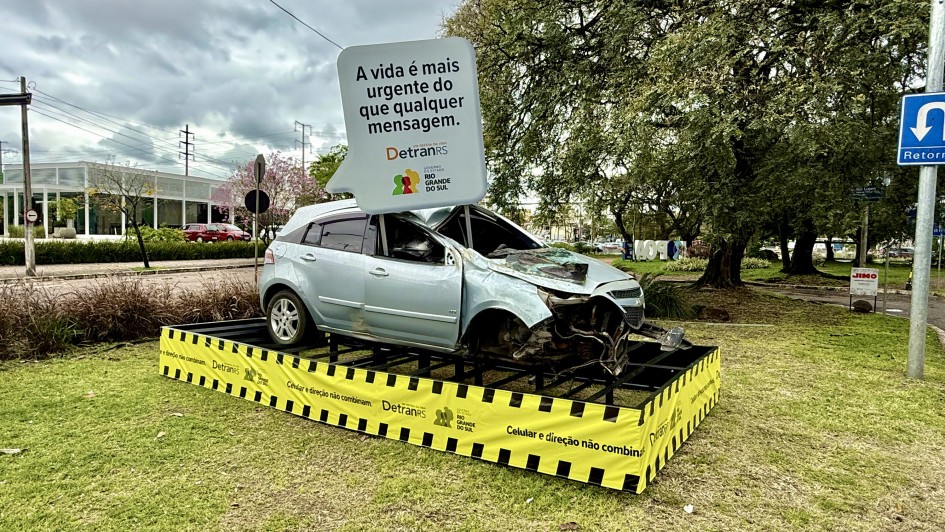 Imagem ao ar livre de um carro acidentado com um balão que remete ao de conversas pelo celular, que diz: A vida é mais urgente do que qualquer mensagem. DetranRS e Governo do Estado do Rio Grande do Sul.